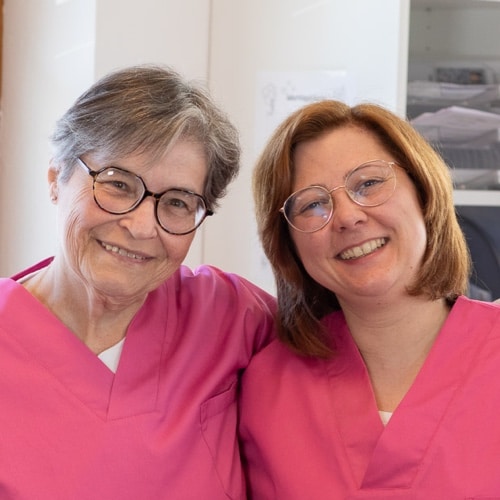 Femeie zâmbitoare cu mâinile la inimă.